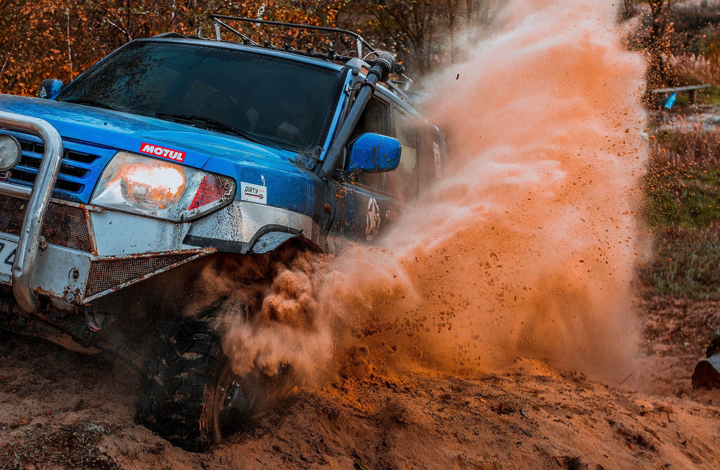 Image of blue off roading vehicle splashing mud to convey off-roading etiquette - Dirt Direct Offroad